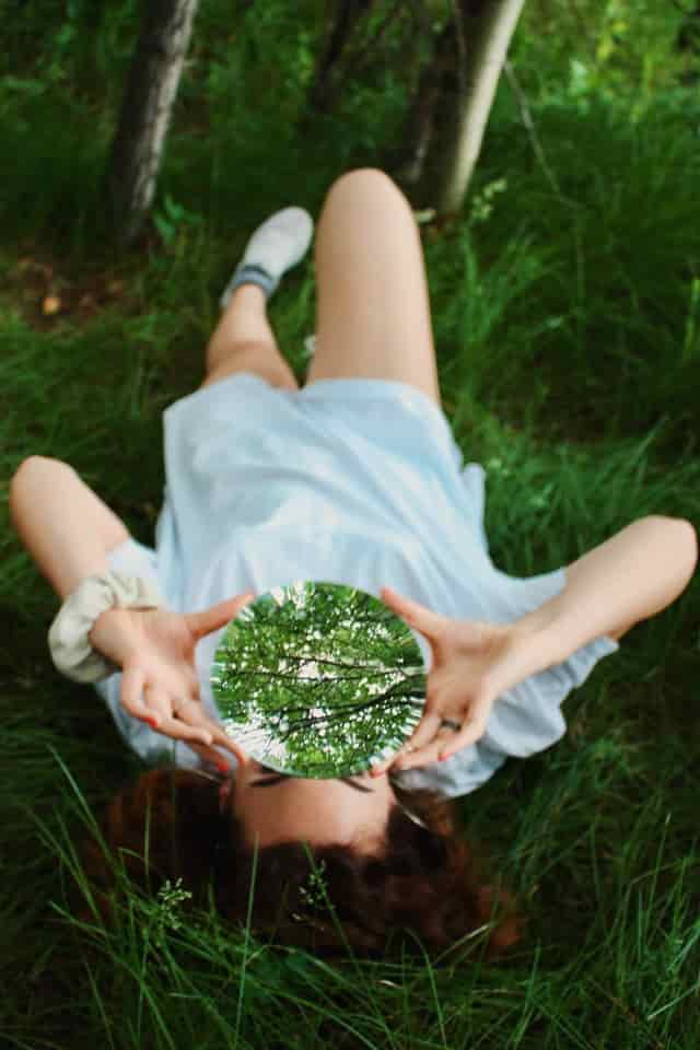 II album cover - a woman lying in a forest, hokding a mirror reflecting the tree